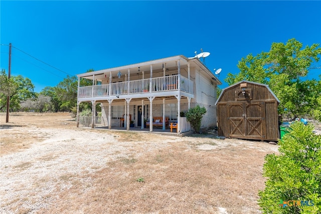 back of house with a balcony and a storage shed