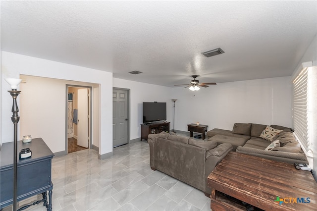 living room with ceiling fan and a textured ceiling