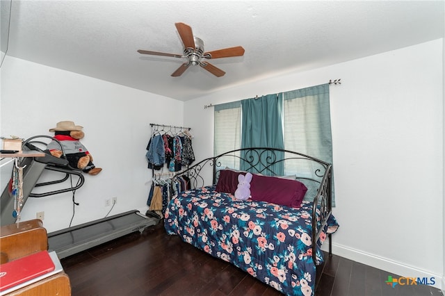 bedroom featuring dark wood-type flooring, ceiling fan, a textured ceiling, and a baseboard heating unit