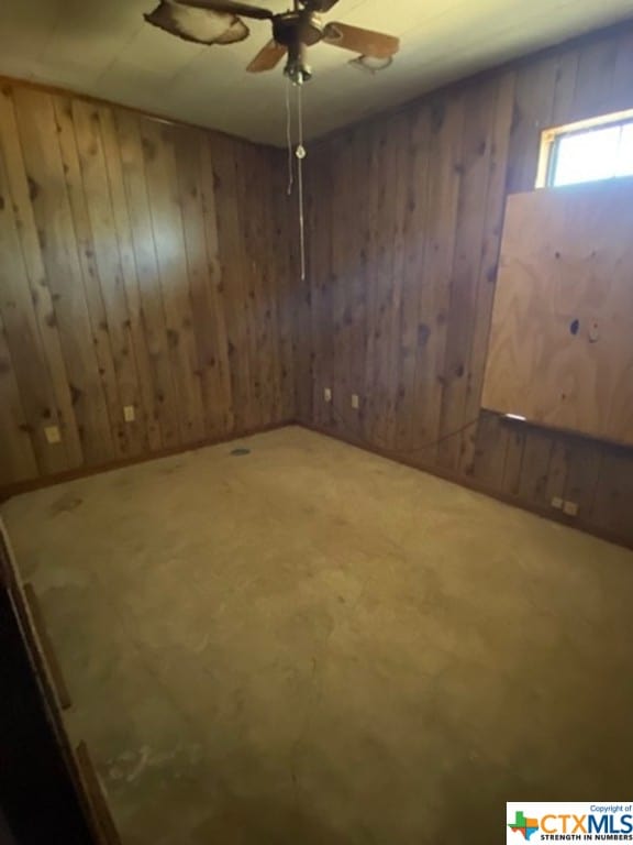 spare room featuring wooden walls and ceiling fan