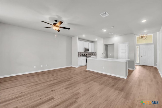 unfurnished living room featuring light wood-type flooring, ceiling fan, and sink