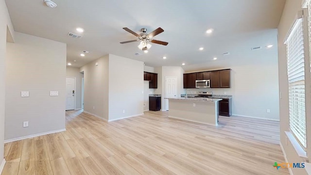 kitchen with sink, ceiling fan, appliances with stainless steel finishes, a center island with sink, and light wood-type flooring