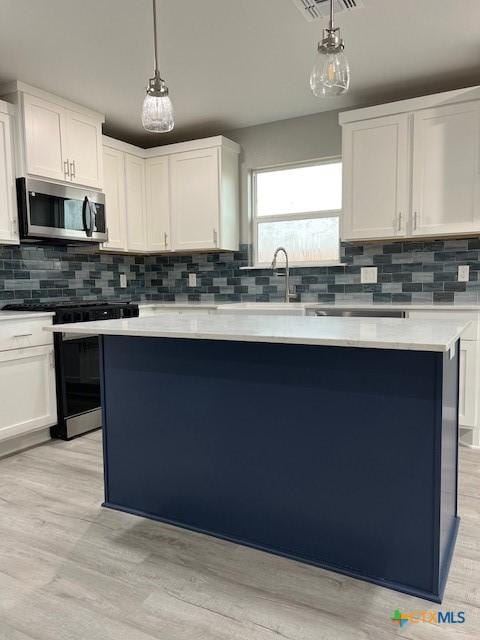 kitchen featuring light countertops, stainless steel microwave, decorative light fixtures, and white cabinetry