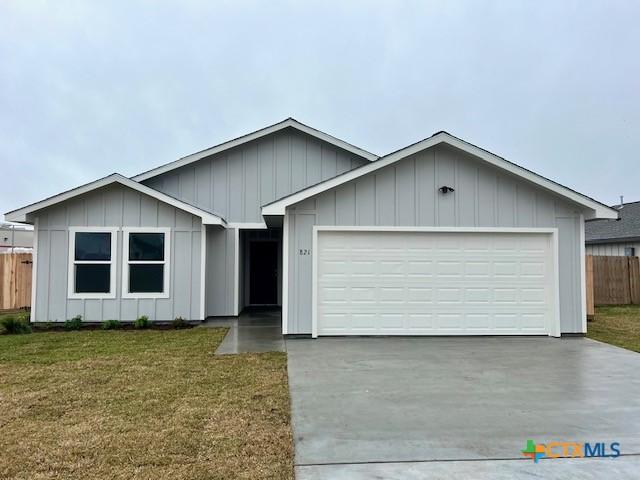 ranch-style house featuring an attached garage, fence, concrete driveway, a front lawn, and board and batten siding