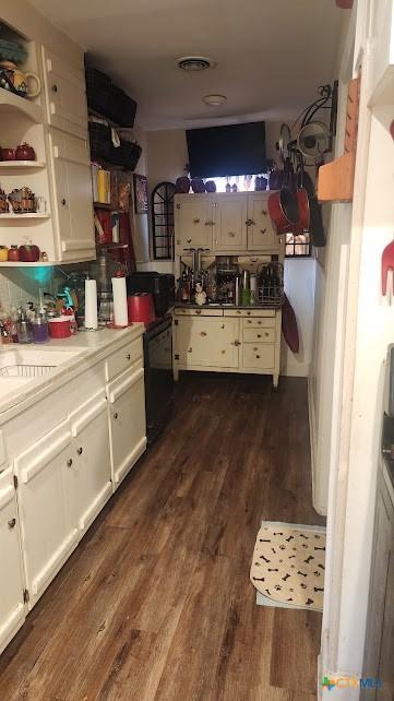 701 E Anaqua Ave, Victoria, TX 77901 - kitchen featuring dishwasher, dark wood-type flooring, white cabinetry, open shelves, and light countertops