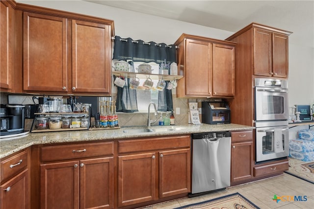 kitchen with backsplash, sink, light tile patterned floors, light stone countertops, and appliances with stainless steel finishes