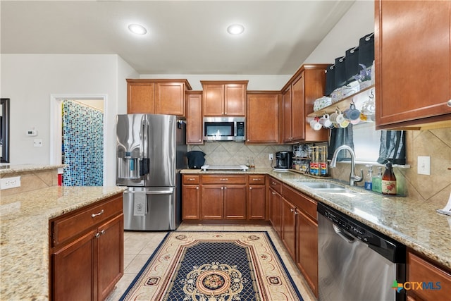 kitchen featuring backsplash, stainless steel appliances, light stone counters, and sink