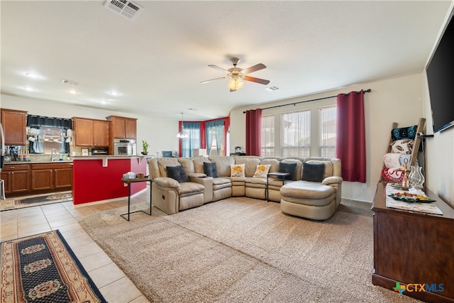 tiled living room featuring ceiling fan and sink