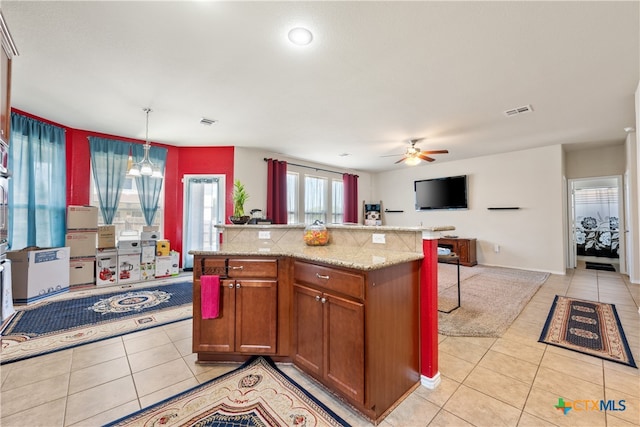 kitchen featuring pendant lighting, ceiling fan with notable chandelier, a center island, and light tile patterned flooring