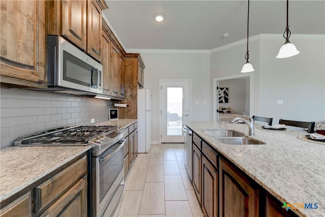 kitchen featuring light stone countertops, appliances with stainless steel finishes, crown molding, sink, and decorative light fixtures