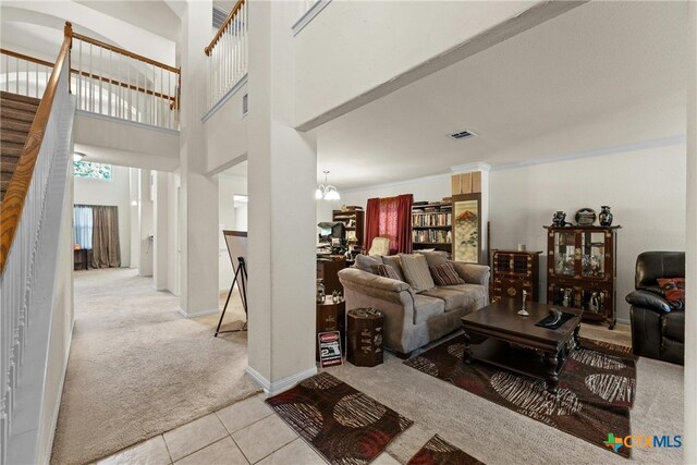 living room with a high ceiling, light colored carpet, and a notable chandelier