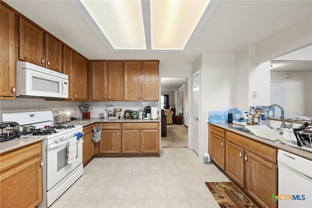 kitchen with decorative backsplash, white appliances, and sink