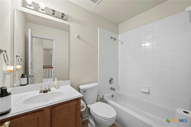 full bathroom with tiled shower / bath, vanity, and toilet