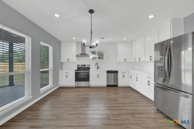 5073 Cedarside, San Marcos, TX 78666 - kitchen featuring stainless steel appliances, wall chimney range hood, a chandelier, dark wood-style floors, and light countertops