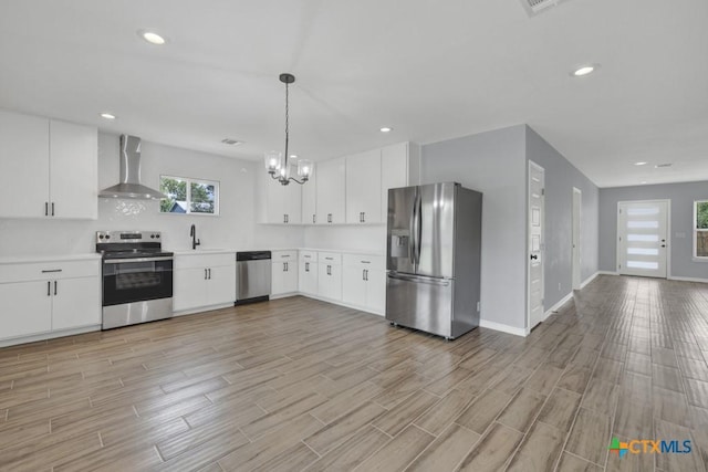 5073 Cedarside, San Marcos, TX 78666 - kitchen with stainless steel appliances, wall chimney exhaust hood, light countertops, light wood-style flooring, and a chandelier