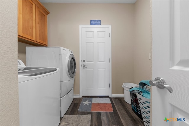 clothes washing area featuring dark wood-type flooring, cabinets, and washer and dryer