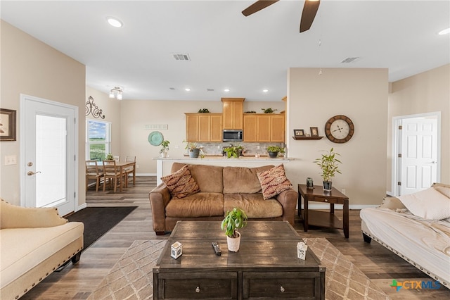 living room featuring ceiling fan and dark hardwood / wood-style floors