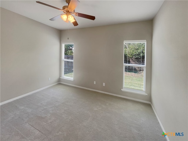 spare room featuring a wealth of natural light, ceiling fan, and light carpet