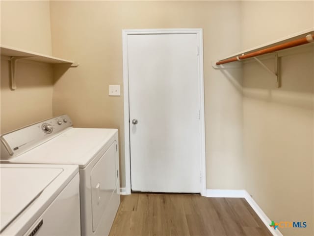 laundry area with light hardwood / wood-style floors and washing machine and clothes dryer