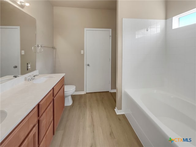 bathroom featuring wood-type flooring, vanity, toilet, and a tub