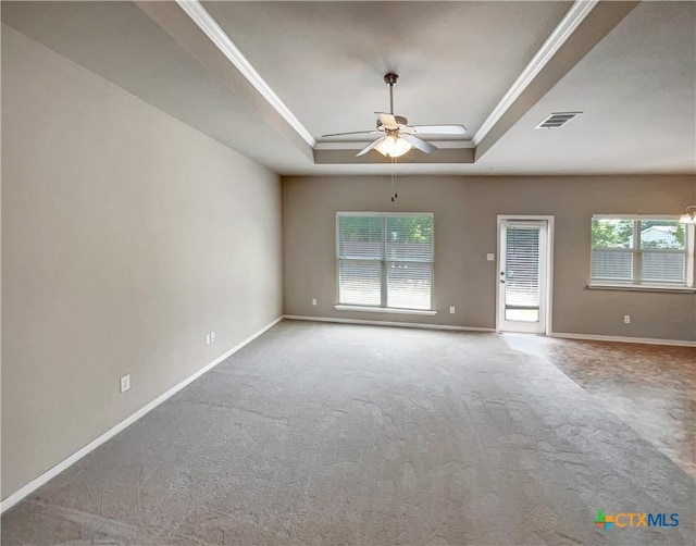 empty room with ceiling fan, ornamental molding, light carpet, and a tray ceiling