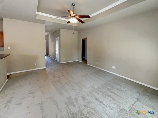 unfurnished living room with ceiling fan, carpet floors, and a tray ceiling