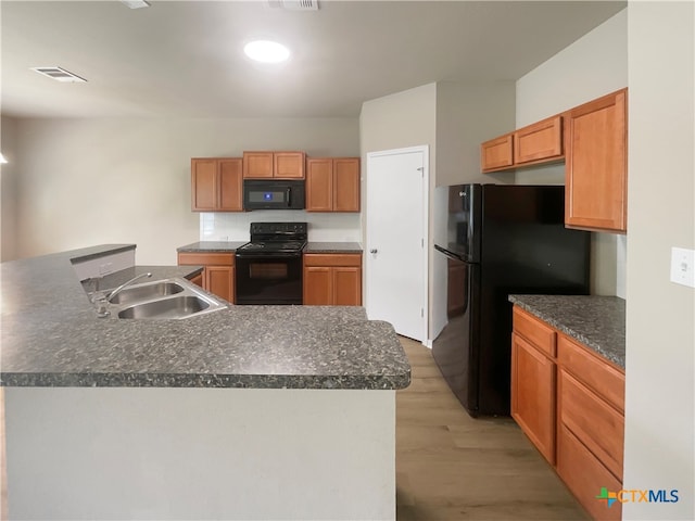 kitchen with black appliances, a center island, light wood-type flooring, and sink