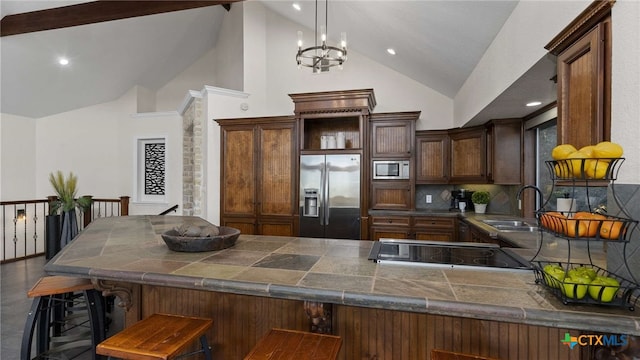 kitchen with a kitchen breakfast bar, kitchen peninsula, built in microwave, tasteful backsplash, and stainless steel fridge with ice dispenser