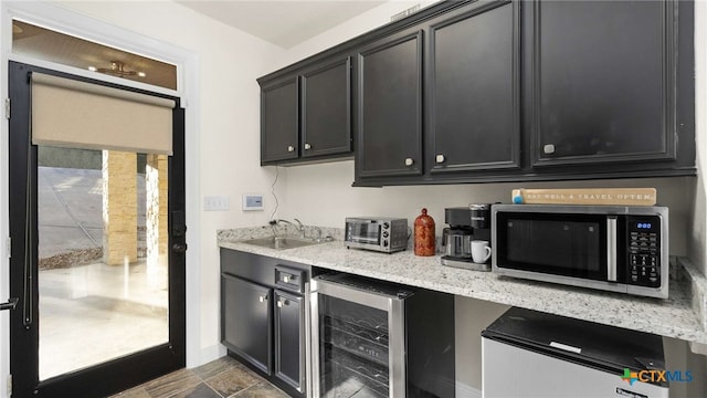 kitchen featuring light stone countertops, sink, and wine cooler