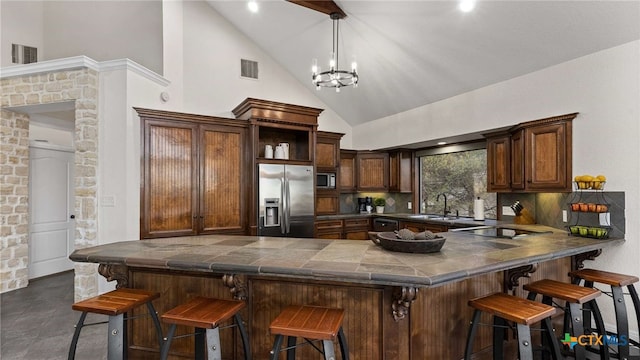 kitchen featuring built in appliances, tasteful backsplash, kitchen peninsula, a breakfast bar area, and a chandelier