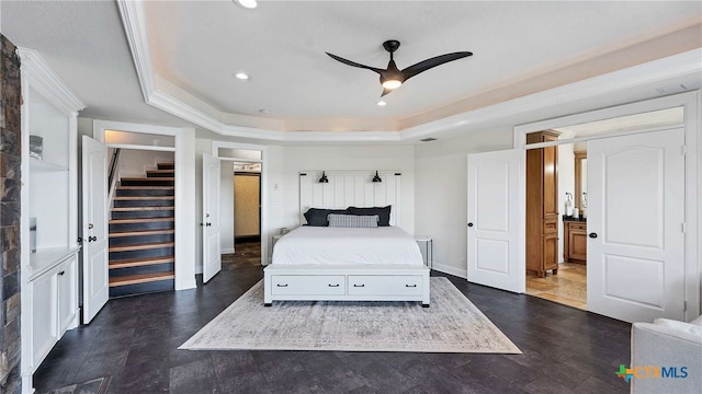 bedroom with connected bathroom, a tray ceiling, ceiling fan, and crown molding