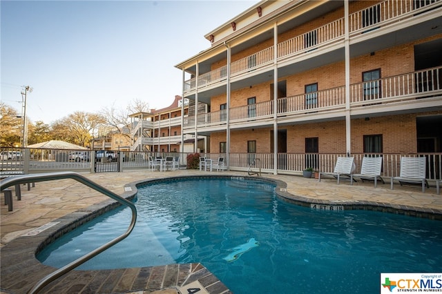 pool with a patio area and fence