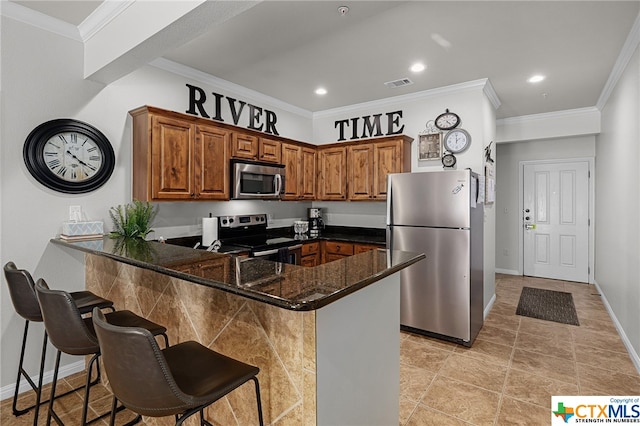 kitchen with crown molding, visible vents, appliances with stainless steel finishes, dark stone counters, and a peninsula