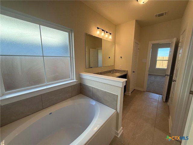 bathroom featuring vanity, tile patterned floors, and a tub to relax in