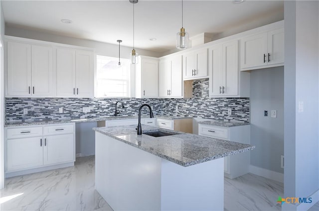 kitchen with pendant lighting, a center island with sink, white cabinetry, and sink