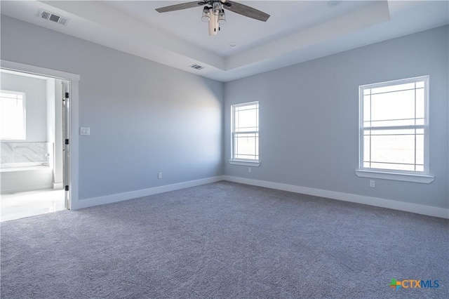 carpeted empty room with a tray ceiling and ceiling fan