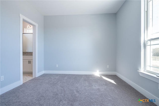 unfurnished bedroom with light colored carpet and connected bathroom