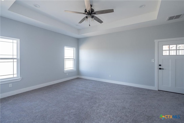 empty room featuring carpet, ceiling fan, and a tray ceiling