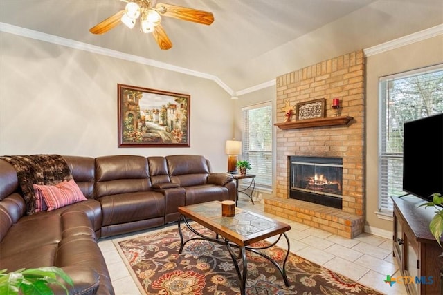 living room featuring lofted ceiling, light tile patterned floors, ceiling fan, ornamental molding, and a brick fireplace