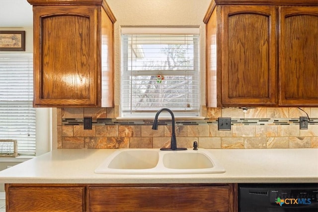 kitchen with black dishwasher, sink, backsplash, and plenty of natural light