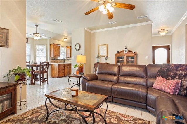 living room featuring light tile patterned floors, crown molding, sink, ceiling fan, and a textured ceiling