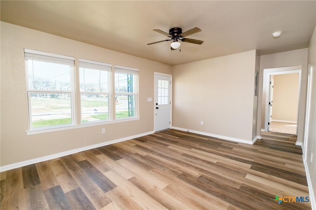 empty room featuring baseboards, a ceiling fan, and wood finished floors