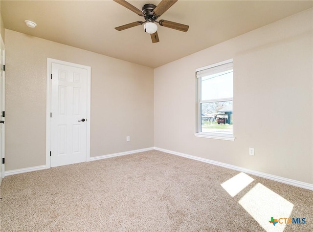 carpeted spare room featuring baseboards and ceiling fan