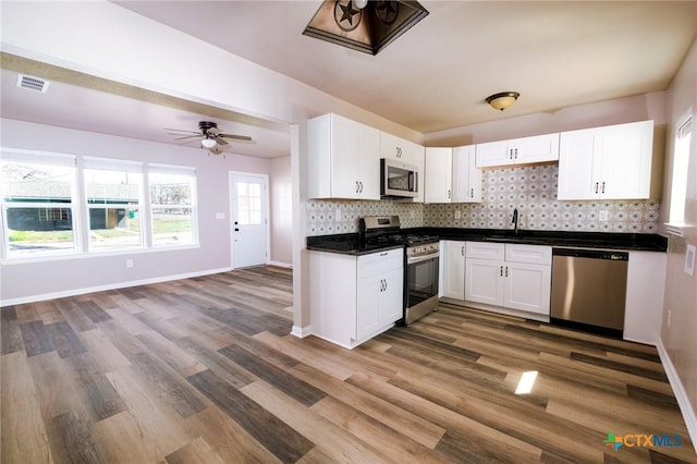 kitchen featuring visible vents, a sink, stainless steel appliances, white cabinets, and tasteful backsplash