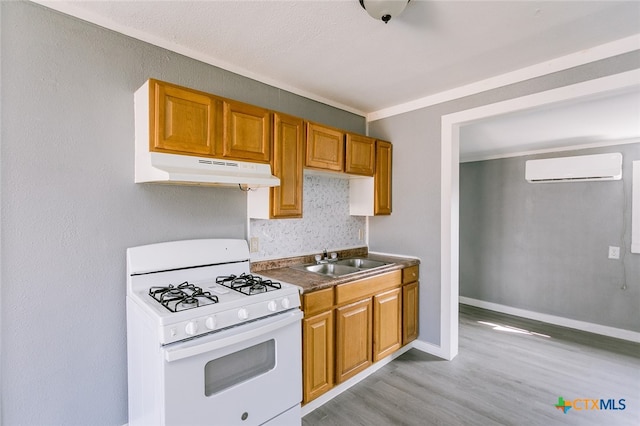 kitchen with a wall mounted AC, light wood-type flooring, white range with gas stovetop, and sink