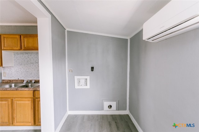 laundry room with electric dryer hookup, a wall mounted AC, sink, ornamental molding, and light hardwood / wood-style flooring