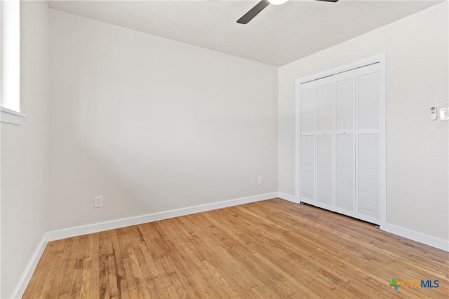 unfurnished bedroom featuring light wood finished floors, a ceiling fan, baseboards, and a closet