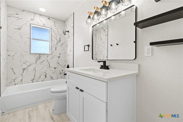 bathroom featuring shower / washtub combination, a textured wall, toilet, vanity, and wood finished floors