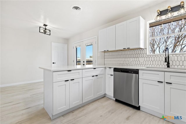 kitchen with light countertops, visible vents, stainless steel dishwasher, white cabinetry, and a sink