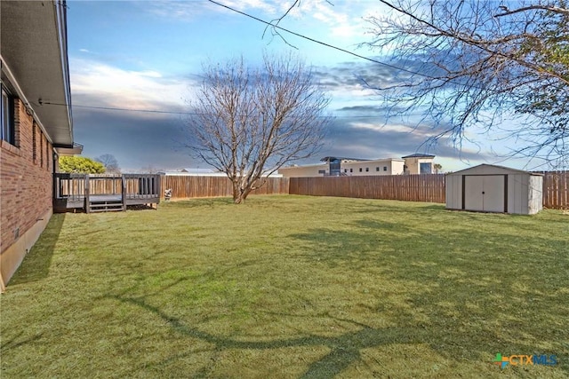 view of yard with a storage shed, a fenced backyard, a deck, and an outdoor structure